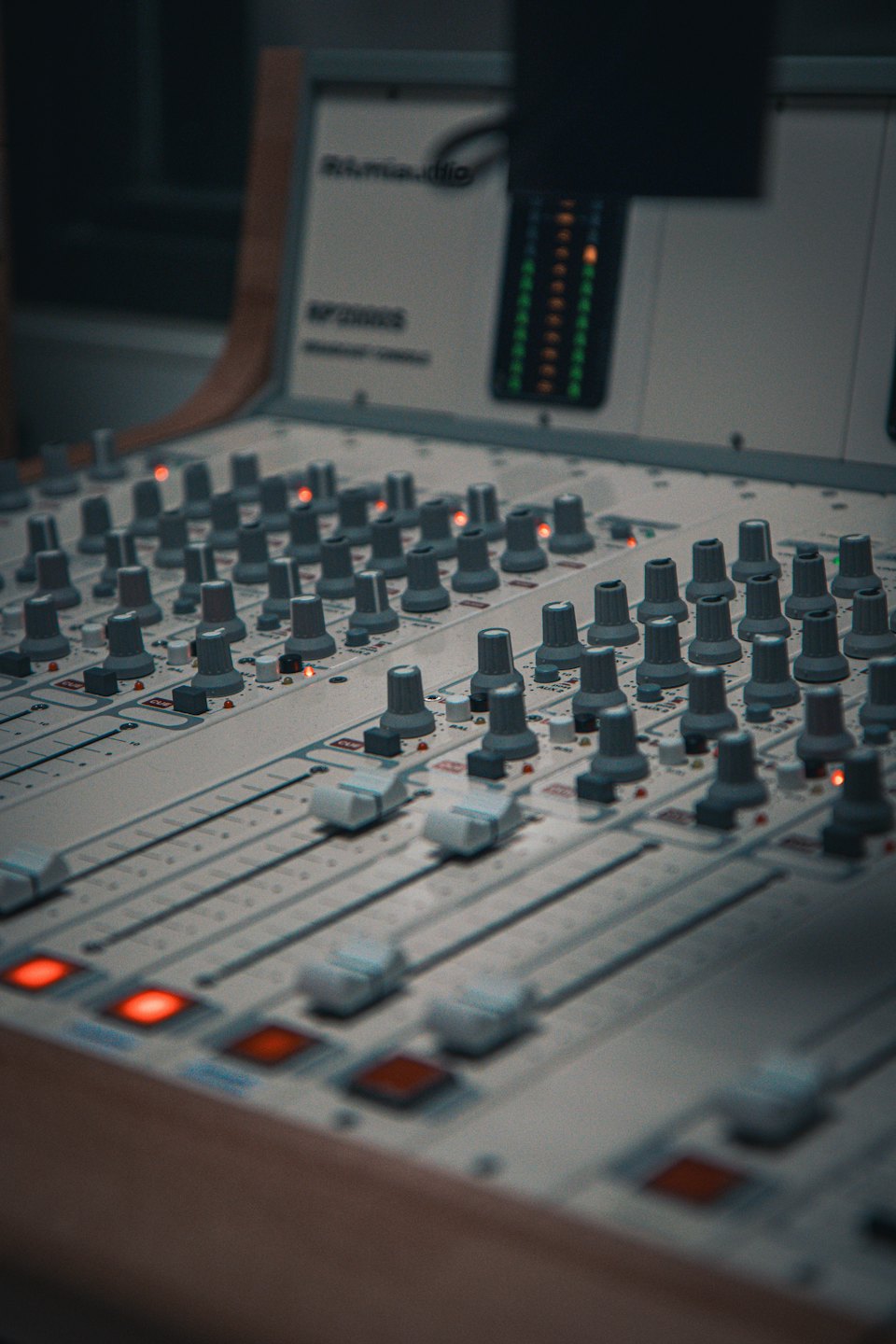 Audio mixing console with faders and indicator lights in a studio.
