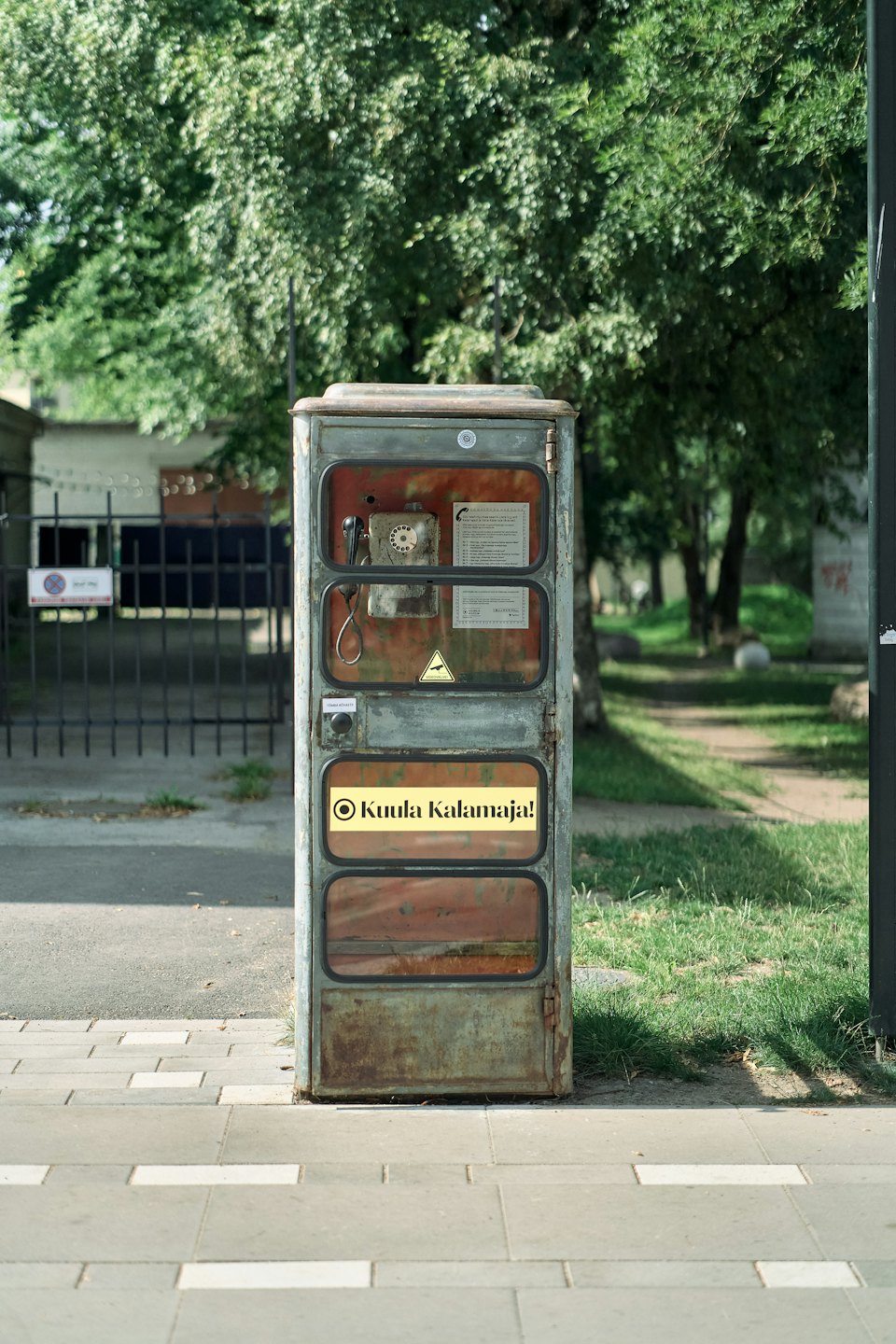 A vintage metal listening station stands on a paved sidewalk.
